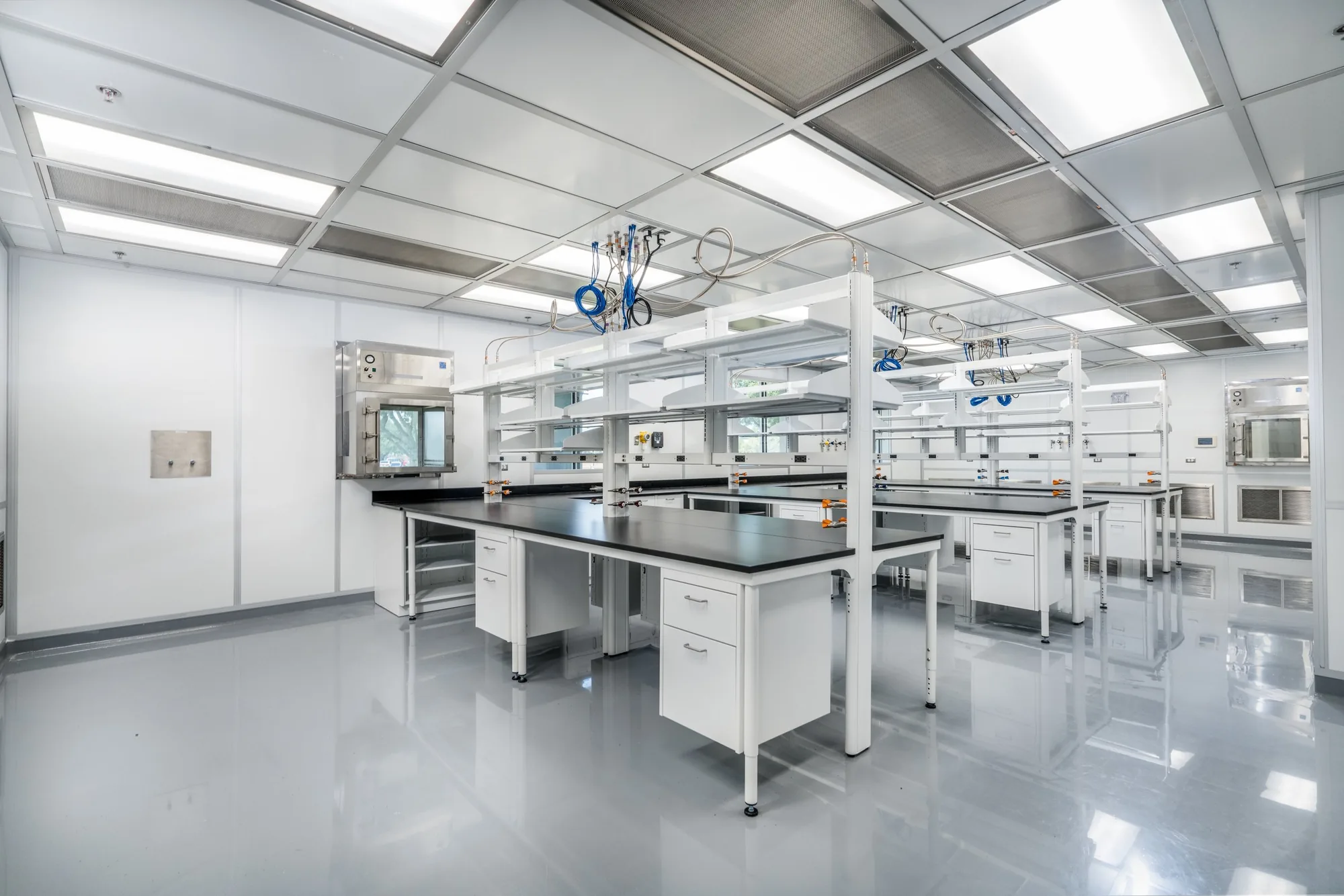 Building 31 clean room at NASA Johnson Space Center, with black lab benches, white cabinets, and overhead utility lines.